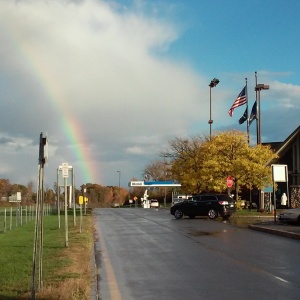 Photo titled "The Road Ahead" by Arden Kirkland. A view of the road at a NY state thruway stop, leading straight to a rainbow in the distance.